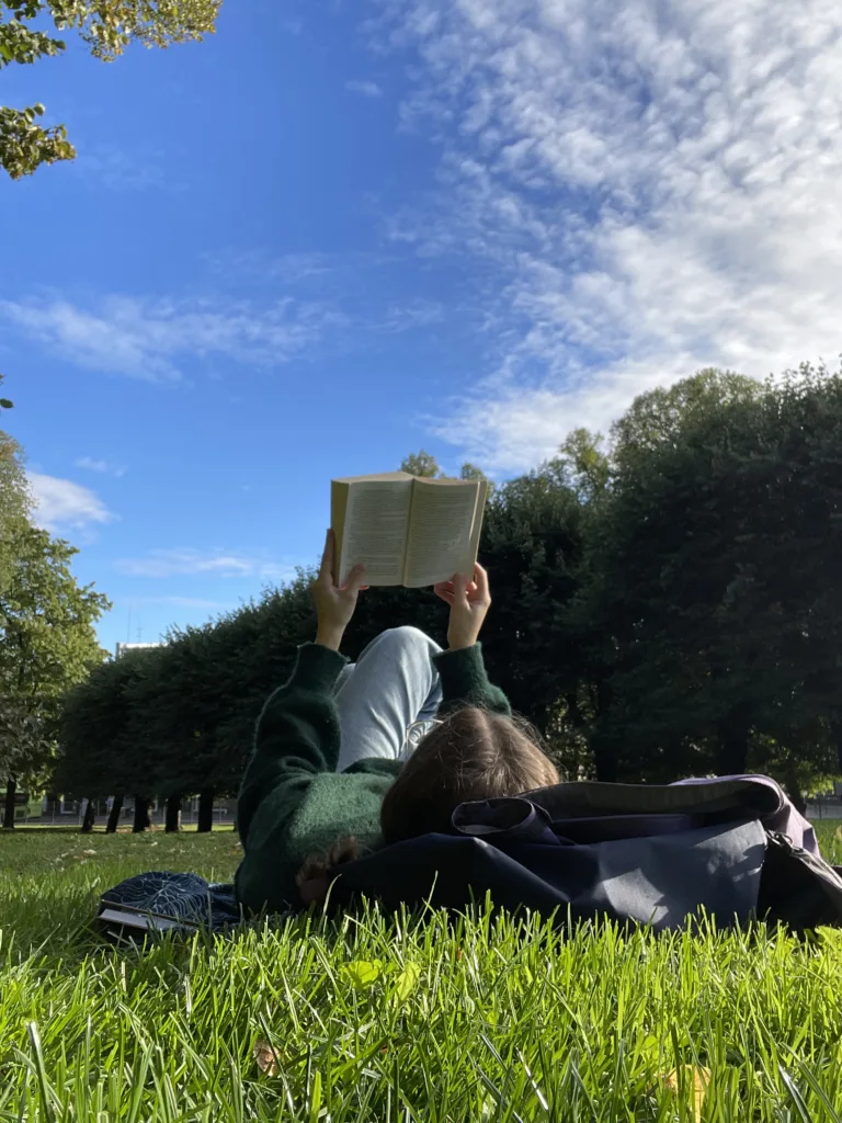 Photo de Maeva Raen couchée sur le dos, lisant un livre